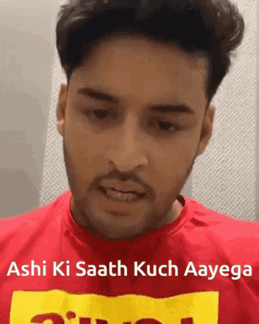 a man wearing a red shirt that says ashi ki saath kuch aayega on it