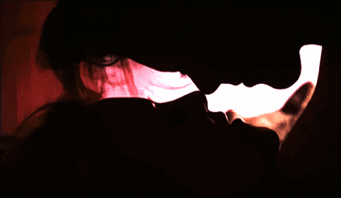 a silhouette of a man and woman kissing in a dark room