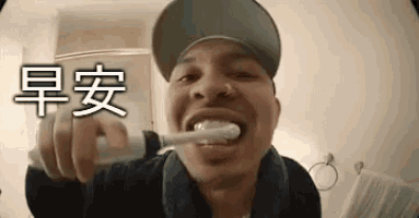 a man in a baseball cap is brushing his teeth in a bathroom .