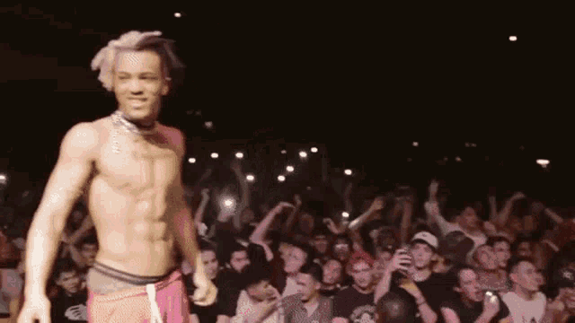a shirtless man is standing on a stage in front of a crowd .