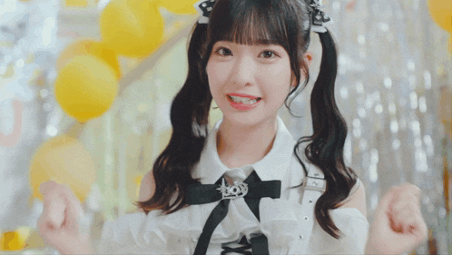 a girl with pigtails is wearing a white shirt with a black bow on it