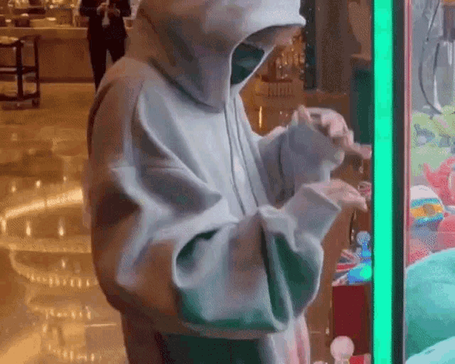 a person wearing a hoodie is standing in front of a machine .