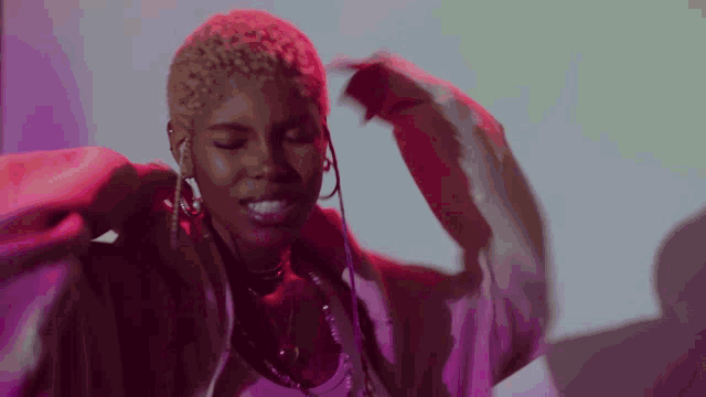 a woman with blonde hair is wearing a pink jacket