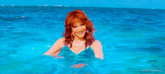 a woman with red hair is swimming in the ocean