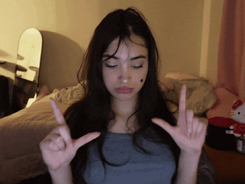 a girl with long dark hair is making a peace sign with her hands