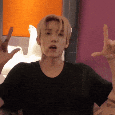 a young man in a black shirt is making a peace sign