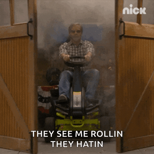 a man is riding a lawn mower with the words they see me rollin they hatin behind him