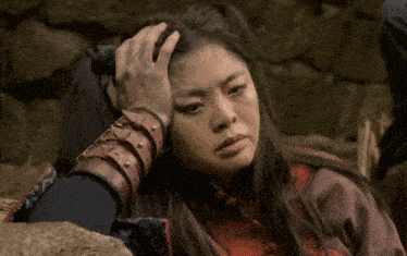 a woman wearing a leather wristband holds her head
