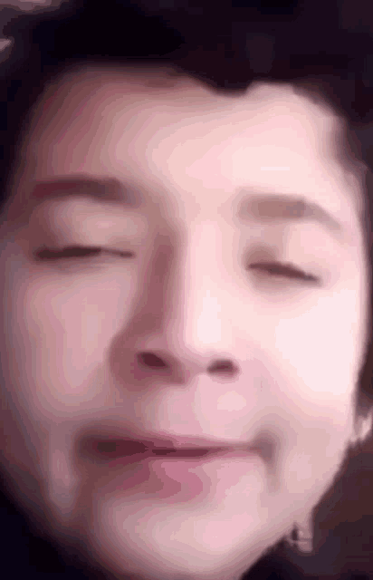 a close up of a boy 's face with his eyes closed .