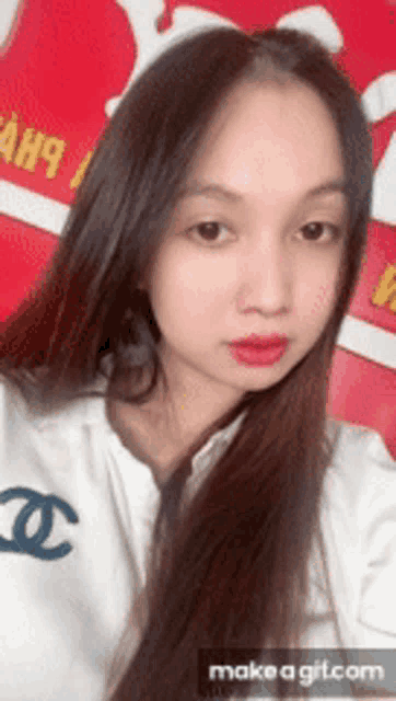 a woman with long hair is wearing a white shirt with a chanel logo on the front