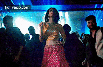 a woman in a red dress is dancing in a club with a group of people .