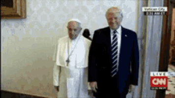 a man in a suit and tie stands next to a man in a white robe in front of a cnn logo