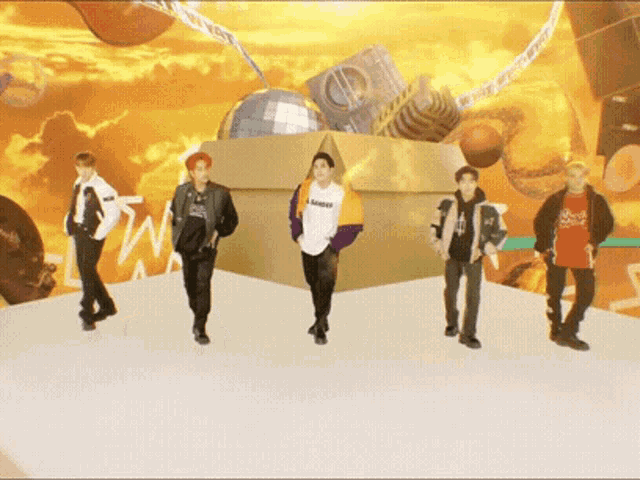 a group of young men are standing in front of a large box that says cd on it