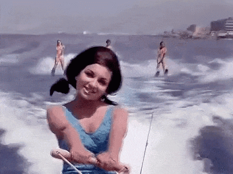 a woman in a blue bathing suit is riding a boat in the water .