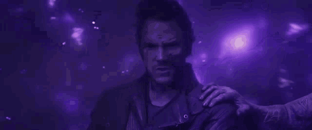 a close up of a man 's face in a dark room with purple lights .