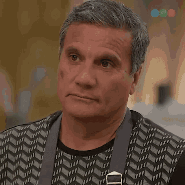 a man with gray hair and a black shirt with a geometric pattern