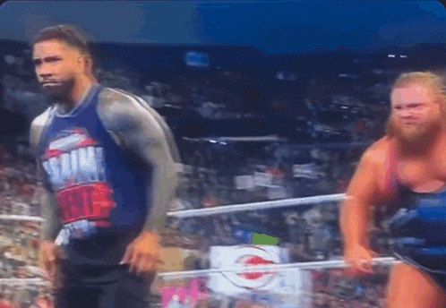 two wrestlers in a ring with one wearing a shirt that says ' smack down '