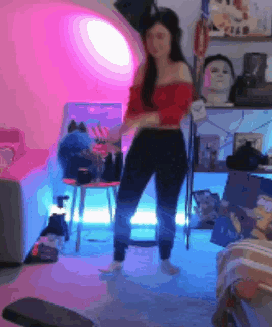 a woman in a red off the shoulder top is dancing in a room with blue lights