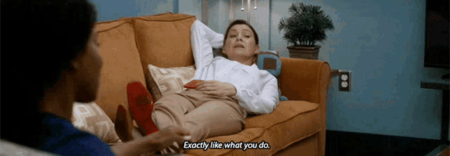 a woman laying on a couch talking to another woman