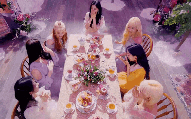 a group of women are sitting around a table with food