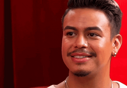 a man with a nose ring and earrings smiles