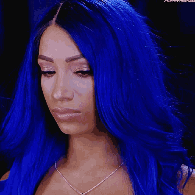 a woman with blue hair is wearing a necklace that says ' the next thing ' on it