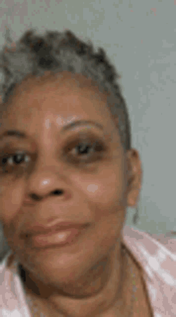a close up of a woman 's face with a shaved head and gray hair .