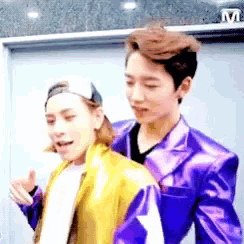 a man in a purple jacket and a man in a yellow jacket are standing next to each other .