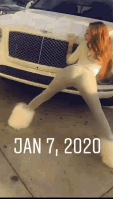 a woman is dancing in front of a white bentley