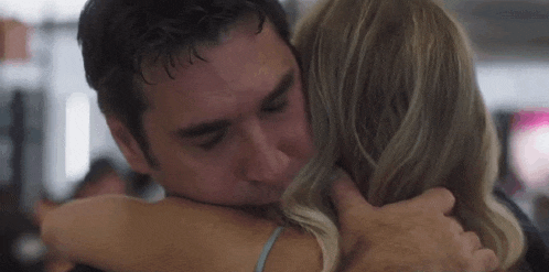 a man and woman are hugging each other in an airport .