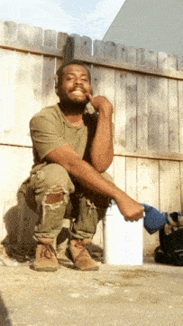 a man squatting down holding a blue bucket