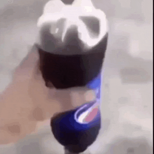 a person is holding a bottle of pepsi in their hand with ice cream coming out of it .