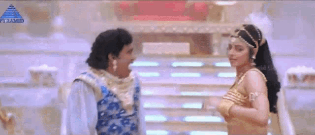 a man and a woman are standing next to each other in a room with a pyramid logo in the background .