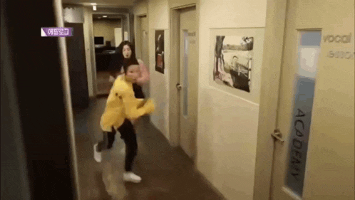 a man in a yellow jacket is walking down a hallway with a woman .