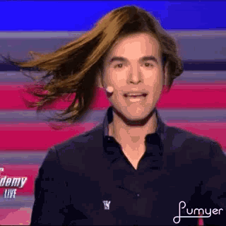 a man with long hair is standing on a stage .