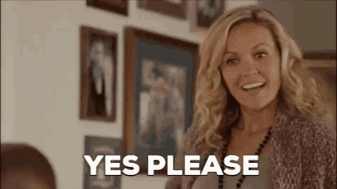a woman is standing in front of a wall of pictures and smiling while saying `` yes please '' .