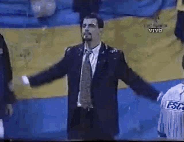 a man in a suit and tie is standing with his arms outstretched in front of a yellow and blue wall .