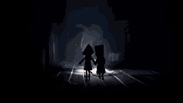 a couple of people standing next to each other in a dark room .