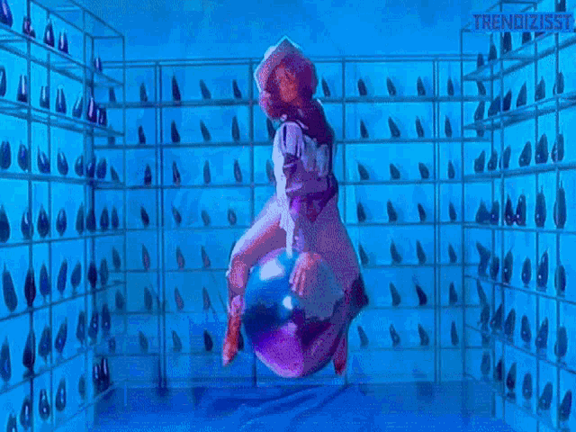 a woman in a cowboy hat is riding a purple object in a room with a lot of shoes on shelves .