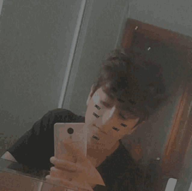 a young man is taking a picture of himself in a mirror with lonely written on his face