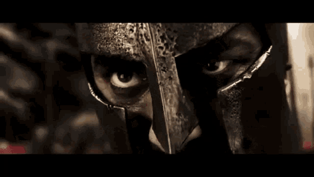 a man wearing a spartan helmet is standing in front of a crowd of soldiers .