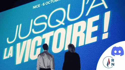 two people standing in front of a large blue screen that says jusqu ' a la victoire
