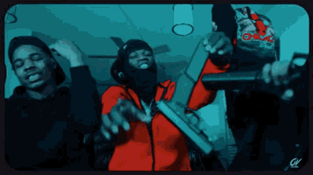 a man in a red jacket is holding a gun in front of another man