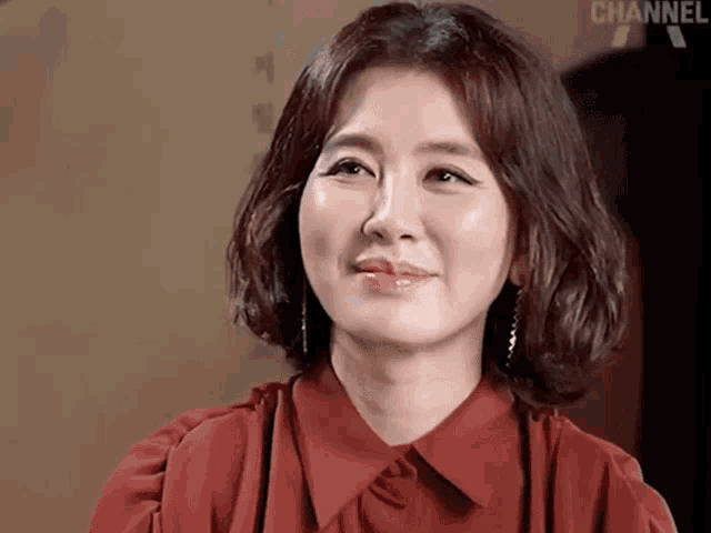 a woman wearing a red shirt and earrings is smiling