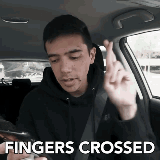 a man in a car with fingers crossed