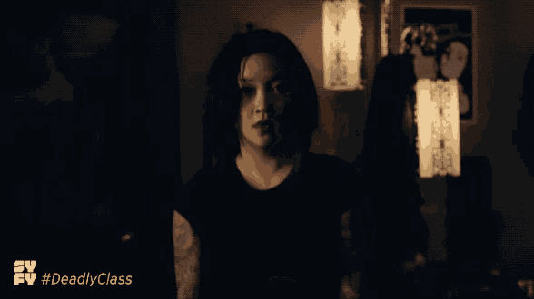 a woman is standing in a dark room with the hashtag #deadlyclass