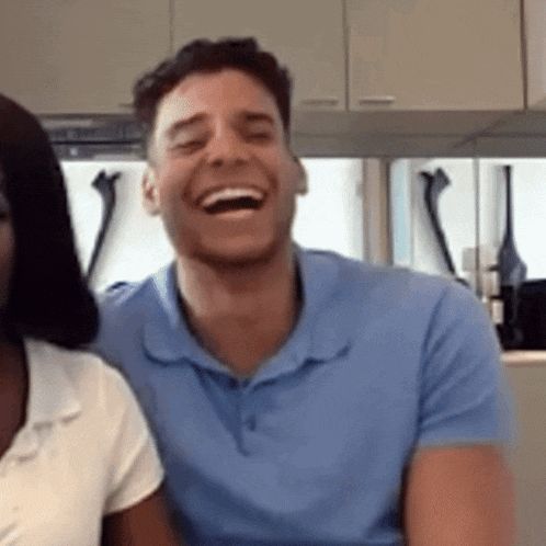a man in a blue shirt is laughing in front of a woman in a white shirt
