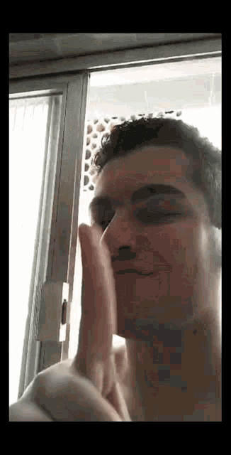 a man is covering his face with his hand while standing in front of a door .