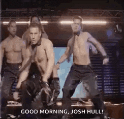 a group of shirtless men are dancing on a stage in a dark room .