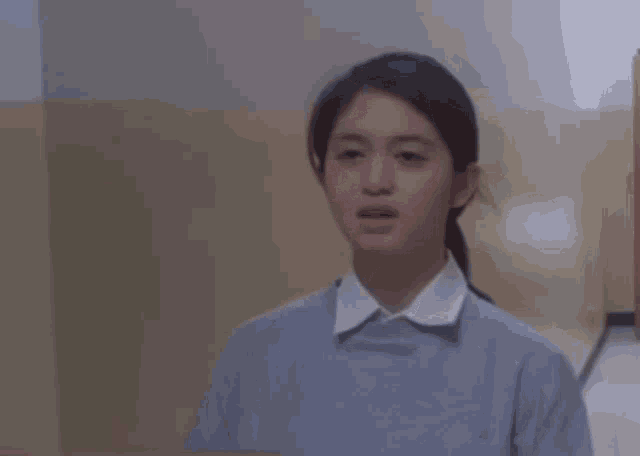 a woman is standing in a hallway with her mouth open and a ponytail .